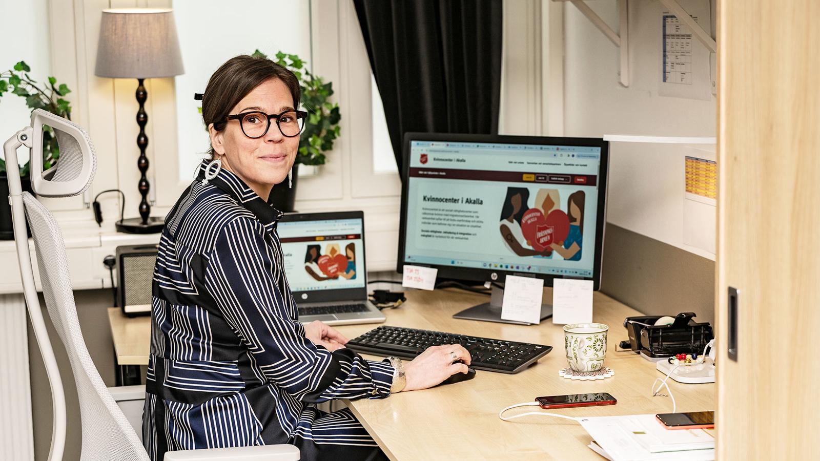 Karin Asplund sitter vid sitt skrivbord och dator på Akalla kvinnocenter.