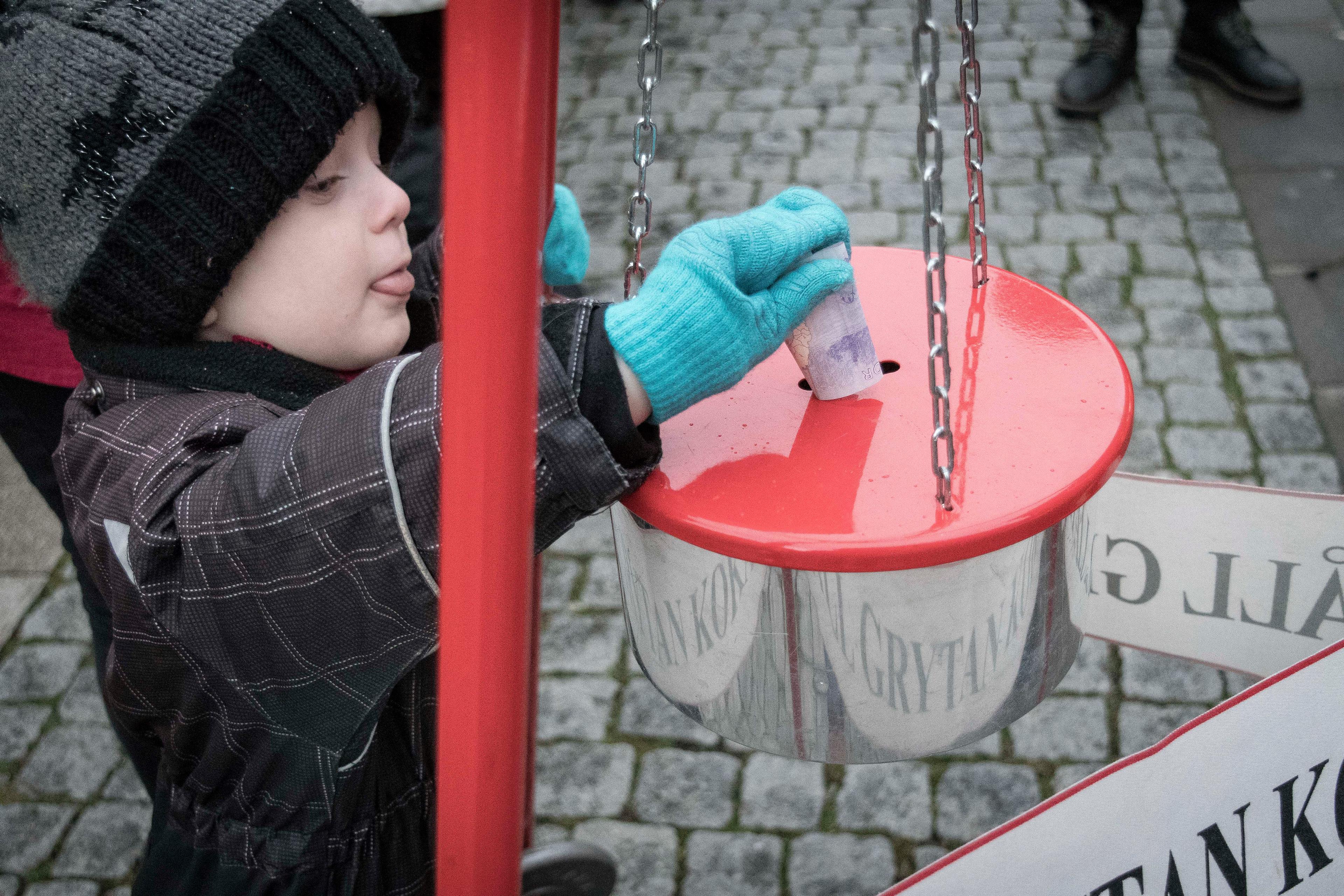 Ett barn som lägger en slant i julgrytan