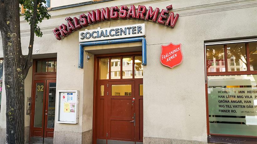 Sociala centrets entré. På fasaden står det "Frälsningsarmén. Socialcenter" och till höger om ingången hänger det en Frälsningsarmén sköld.