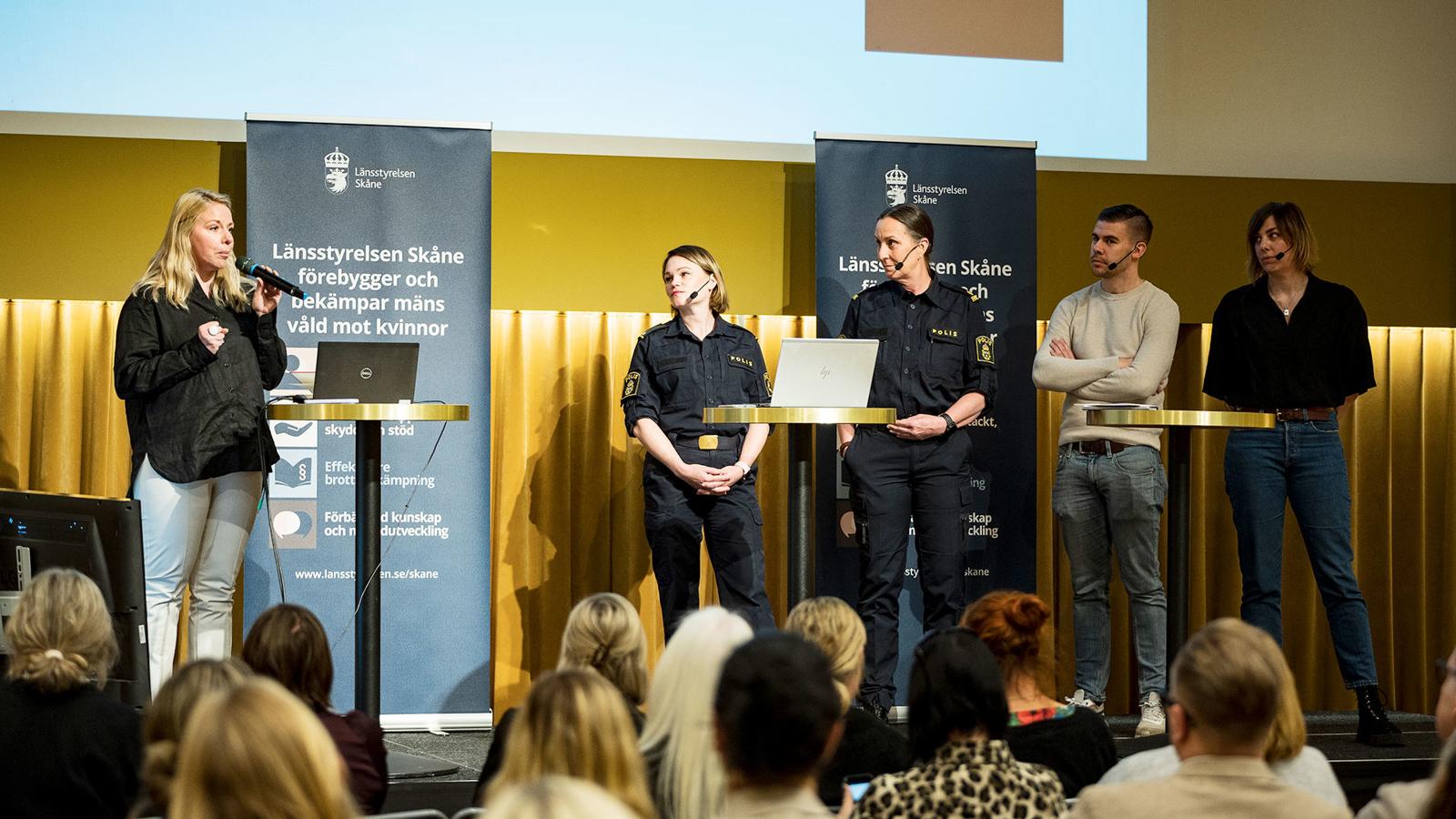 Madeleine Sundell står på scen vid en konferens i Malmö om människohandel. På sen står också fyra stycken poliser som deltar i ett panelsamtal kring ämnet.  deltar i 