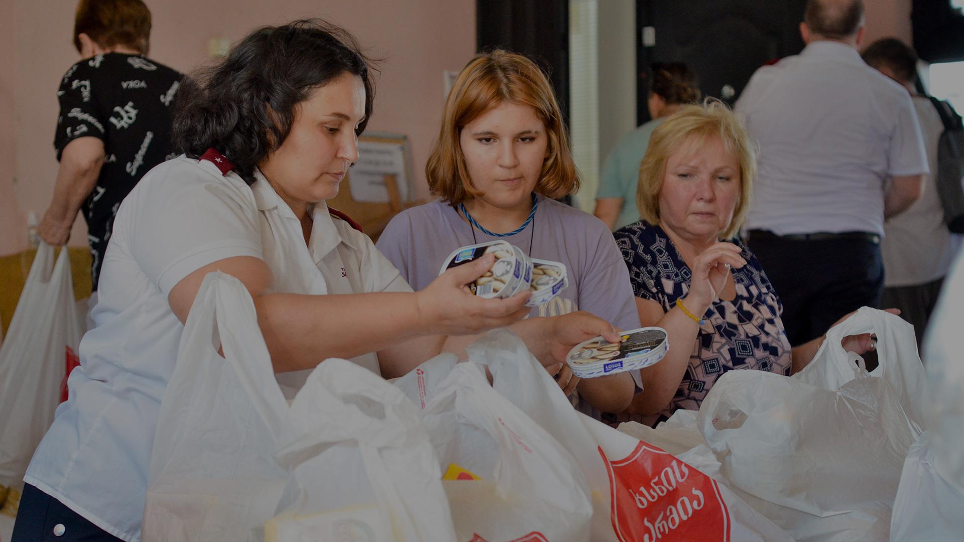 Tre kvinnor packar matkassar avsedda för människor utsatta för kriget i Ukraina.