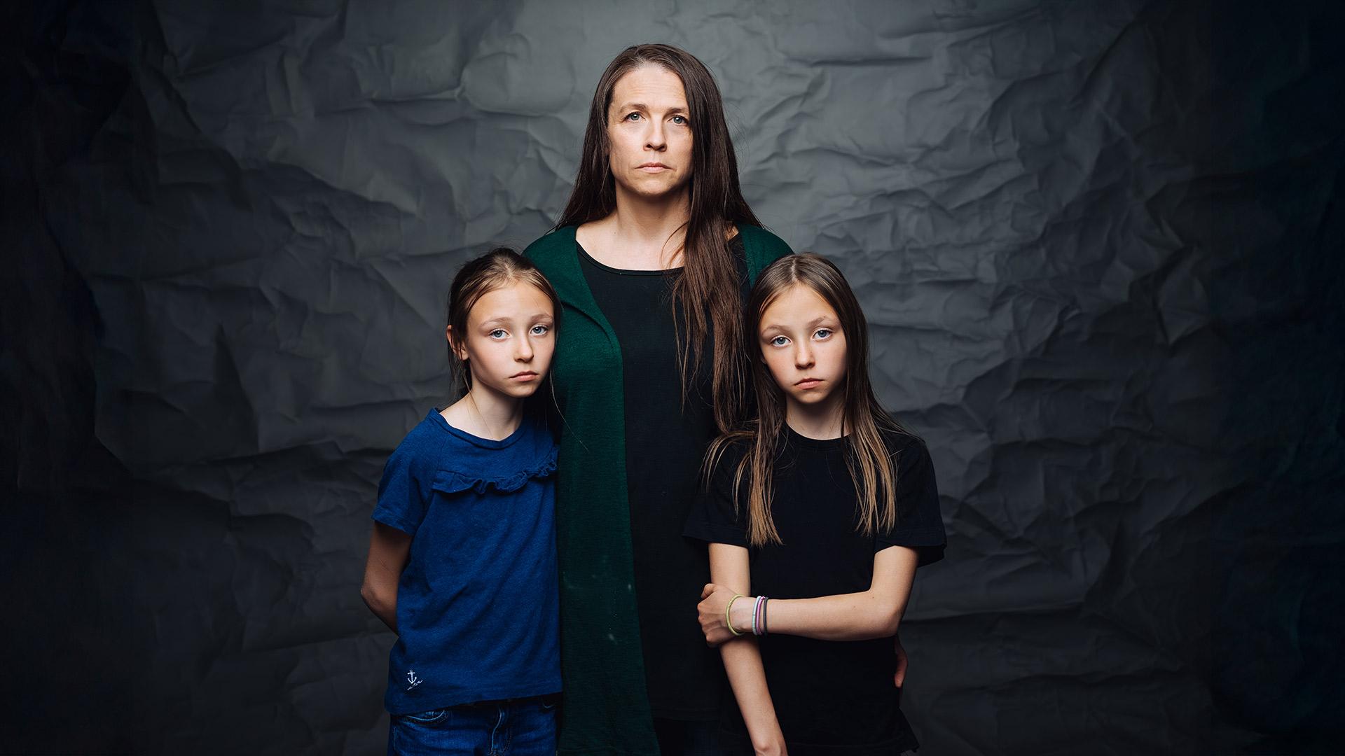 En allvarsam mamma med två flickor framför sig