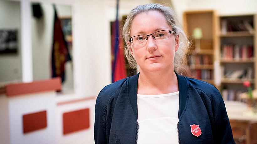 Bodil Nilsson som är verksamhetschef på Sociala centret. Hon ler mot kameran. I bakgrunden syns två bokhyllor och två röda flaggor.